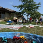 kiddie pool full of mud and toy construction vehicles in front of muddy participants playing in the dirt