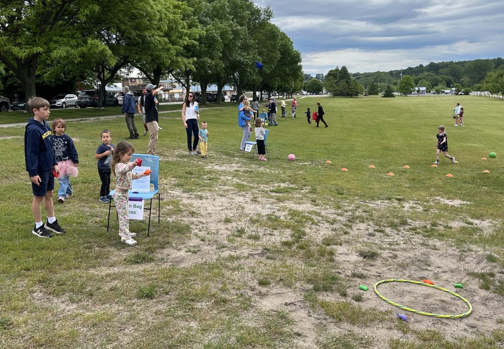 Children in an open field playing yard games and sports challenges