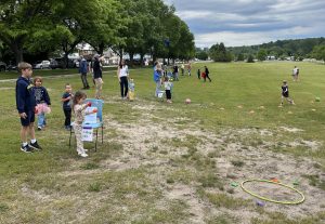 Children in an open field playing yard games and sports challenges